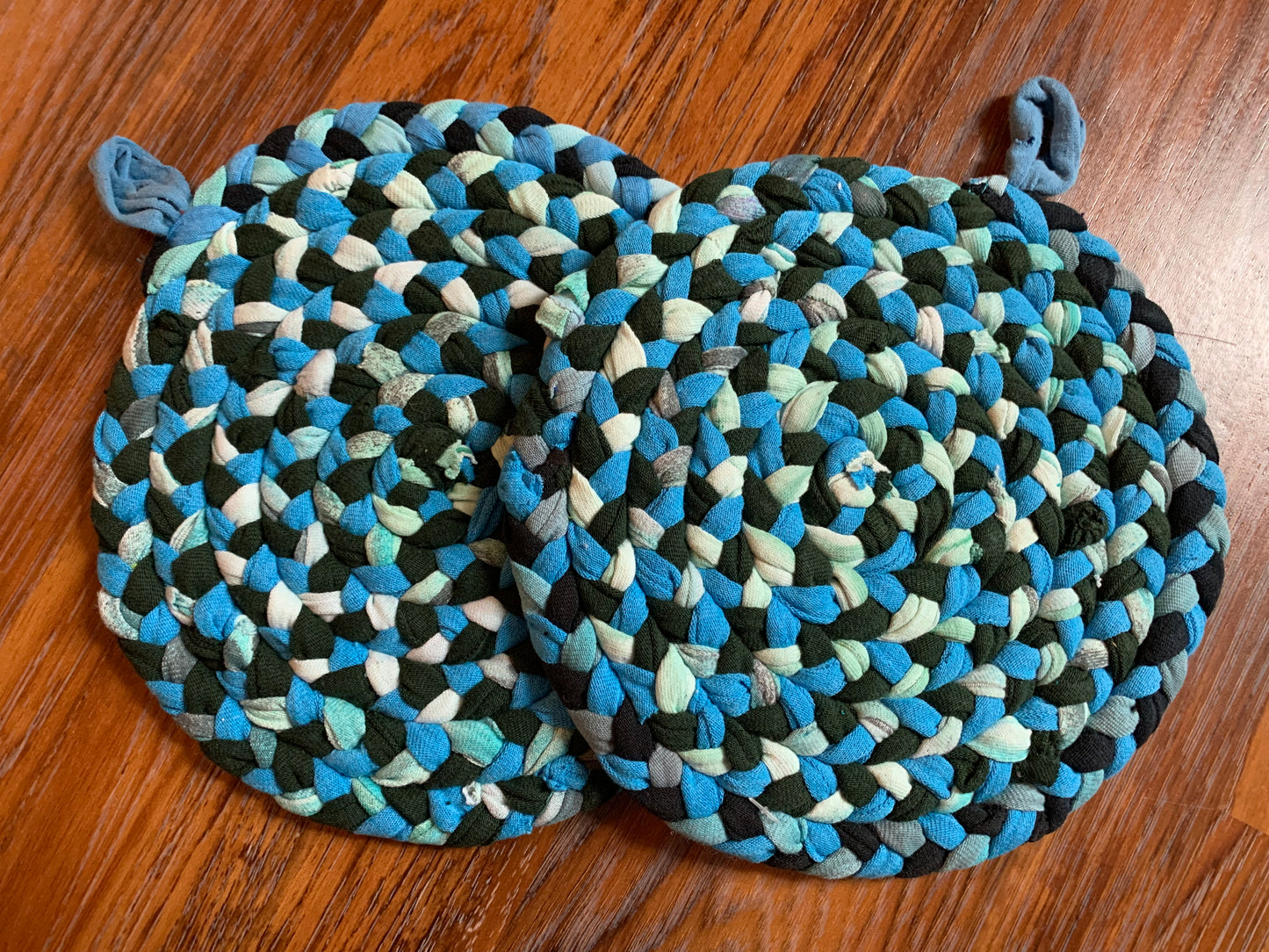 hand braided and hand sewn potholder/trivets set flat lay against a wood background