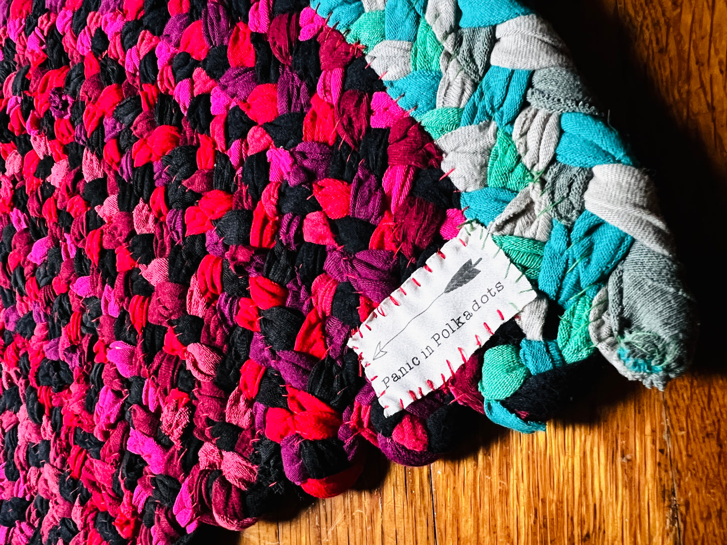 watermelon rug, closeup of label with had an arrow and the words "Panic in Polkadots"