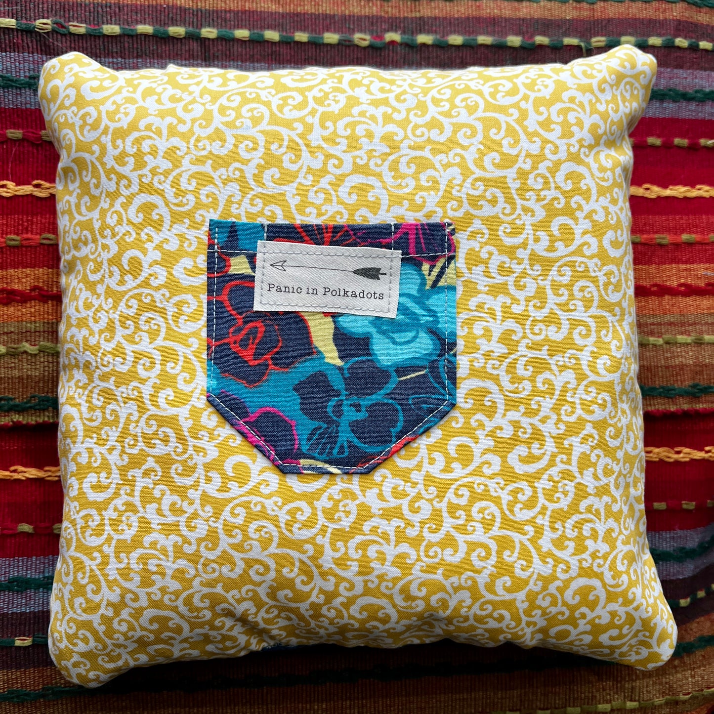 back view of wizrd of oz cathedral square pillow, with swirling yellow print and vibrant floral pocket